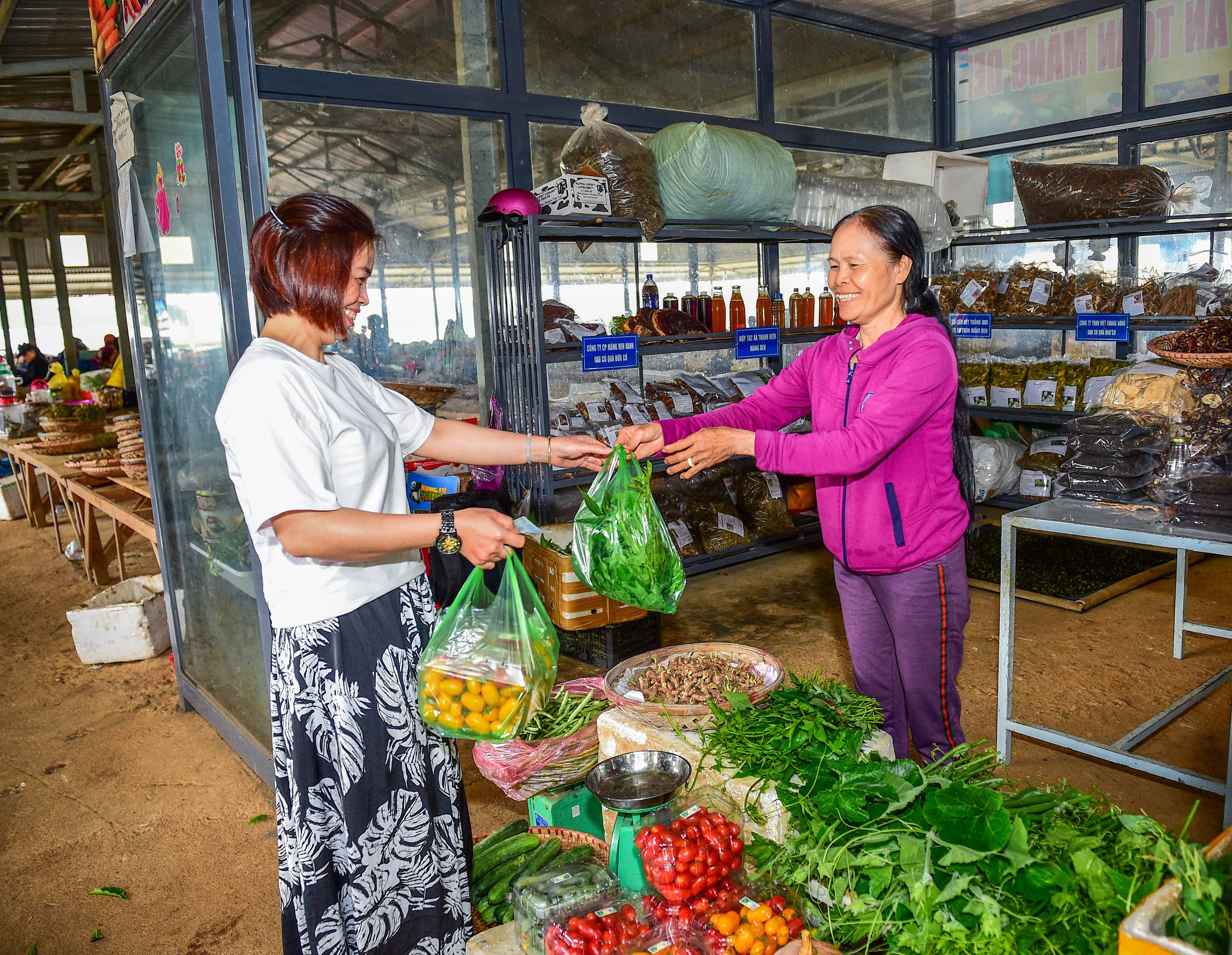 Chị Phan Thị Thanh Hoa (bên phải) bán rau cho khách tại chợ trung tâm huyện Kon Plông